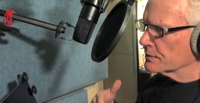 Person med hörlurar talar in i mikrofon i en ljudstudio